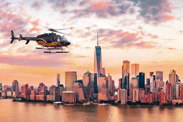 Helicopter flying over New York City skyline at sunset.