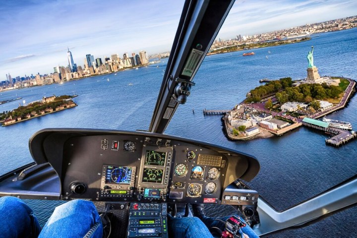 View from a helicopter cockpit over the Statue of Liberty and Manhattan skyline.
