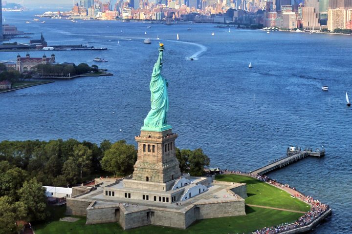 aerial view of statue of liberty on water with new york city in background