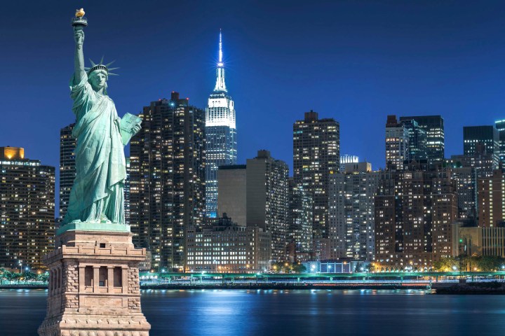 Statue of Liberty with New York City skyline at night.